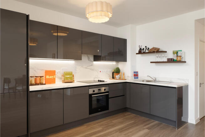 Angled photograph towards grey kitchen with dark wood flooring
