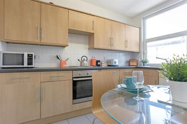 Bright modern kitchen with light wood cabinets,...