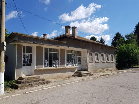 Side perspective of the bakery building showing entrance doors and windows with posted notices