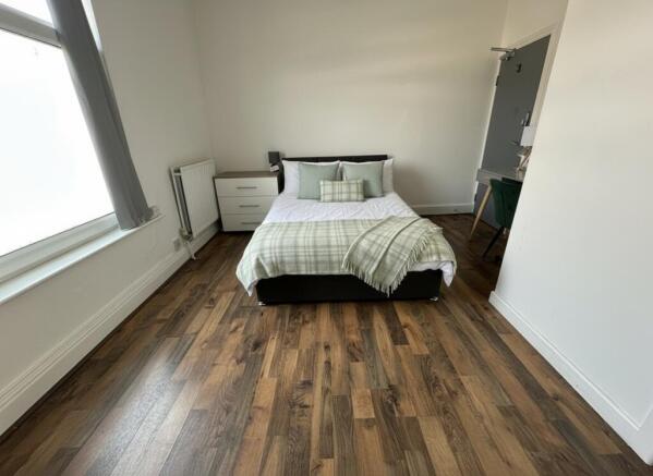 Spacious bright bedroom with wood-effect floors...