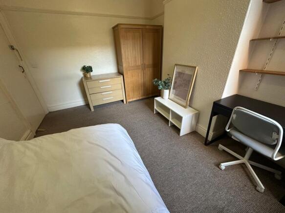 A cozy single bedroom featuring a neatly made b...