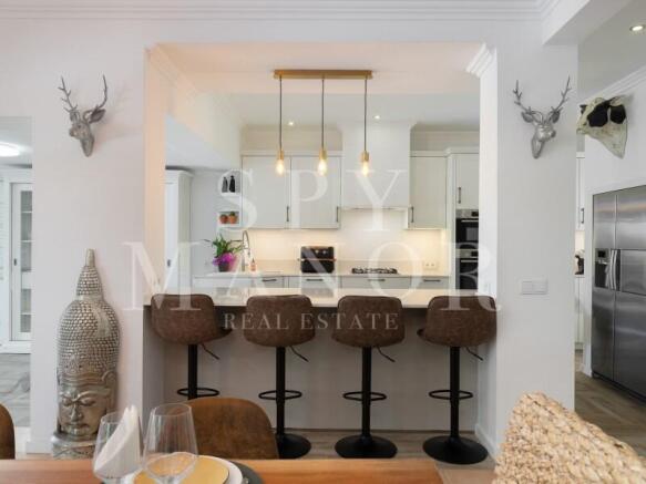 Brand-new designer open-plan kitchen in a renovated Algarvian Quinta. Modern kitchen bar with four stools, elegant pendant lights, and contemporary decor.