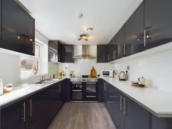 Modern galley-style kitchen with glossy dark ca...