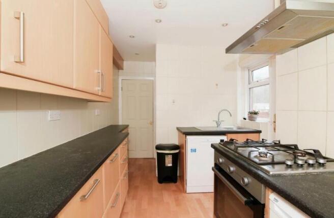 Bright galley-style kitchen with light wood cab...