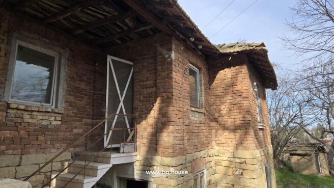 Side perspective of the brick house featuring white-framed windows and a metal staircase leading to an upper door