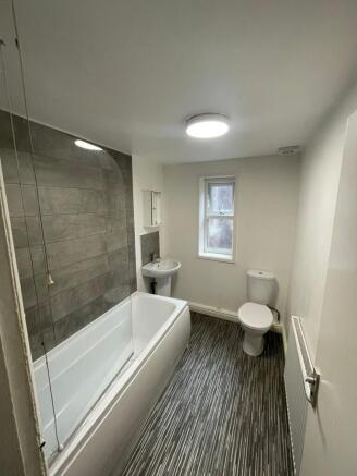 A spacious and modern bathroom featuring a bath...
