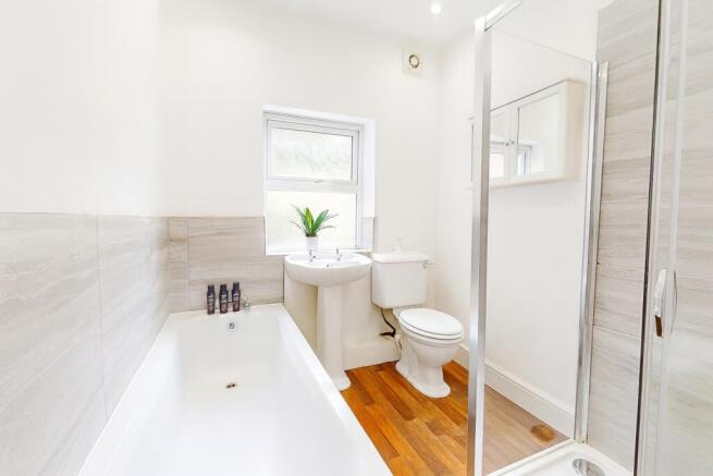 Bright, modern bathroom with a white bathtub, p...
