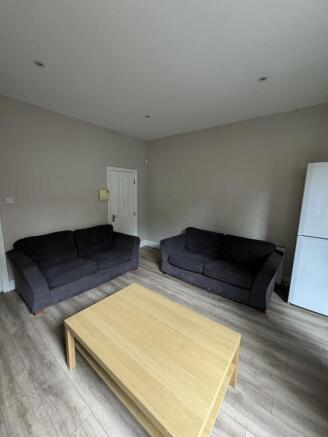 Bright shared living room with two dark sofas f...