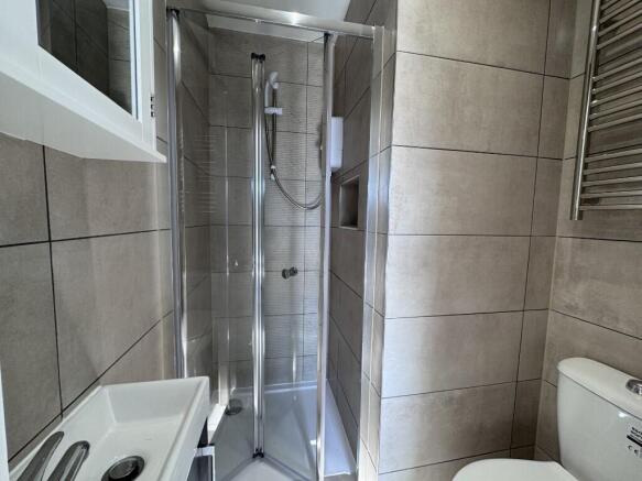 Modern tiled bathroom with a corner glass showe...