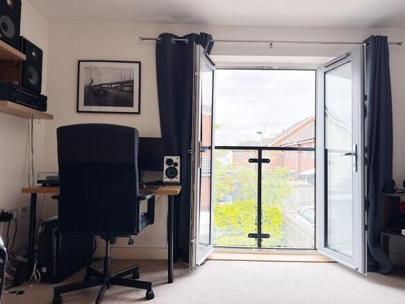 Bright bedroom with a desk workspace and balcon...