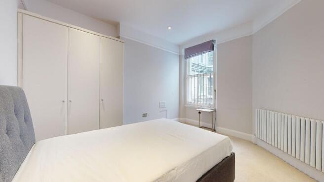 A neat and tidy double bedroom featuring a comf...