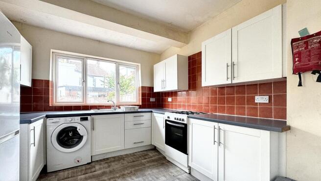 Bright, modern kitchen with white cabinetry, in...