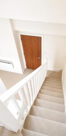 Bright, carpeted staircase with modern white tr...