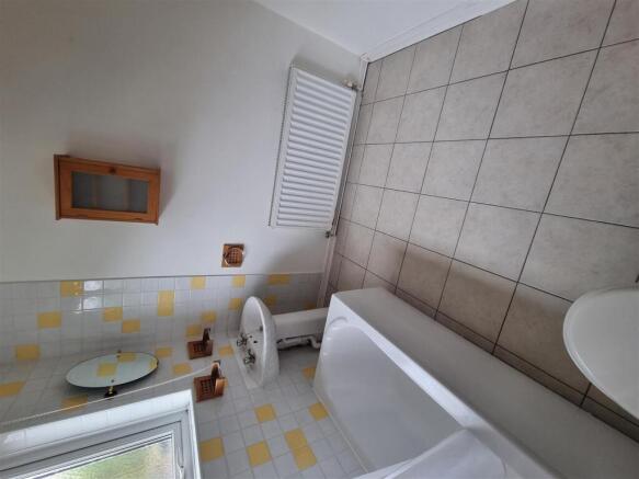 Bright bathroom with full tub and tiled floorin...