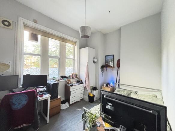 A modest bedroom with a window providing natura...