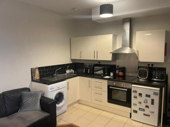 Modern open-plan kitchenette with cream cabinet...