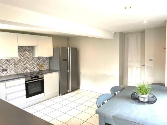 Modern kitchen featuring sleek white cabinetry,...