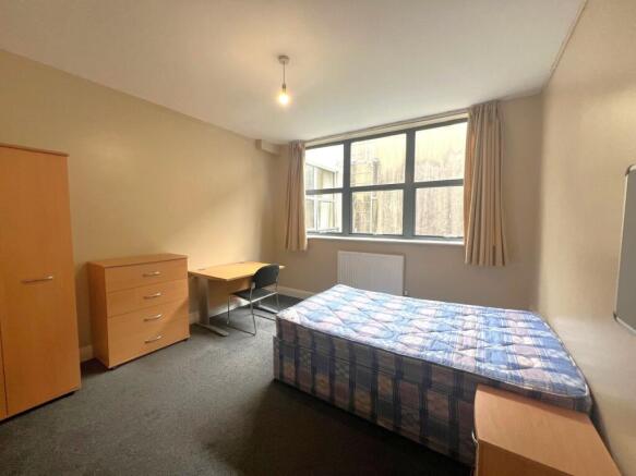 Bright, simply furnished bedroom with a large w...