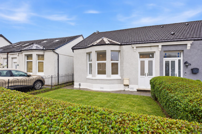 Tidy Grey Bungalow with Trimmed Hedges.png