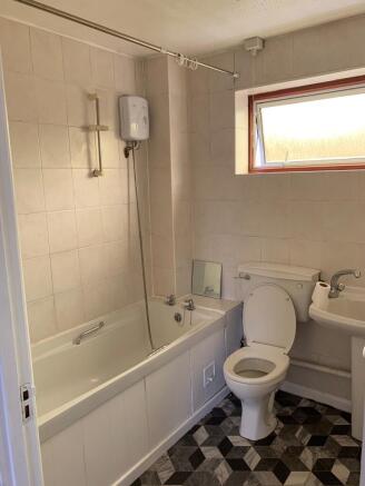 A clean and well-lit bathroom featuring a bath,...