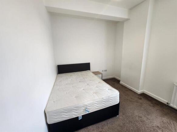 A clean and bright bedroom featuring a bed fram...