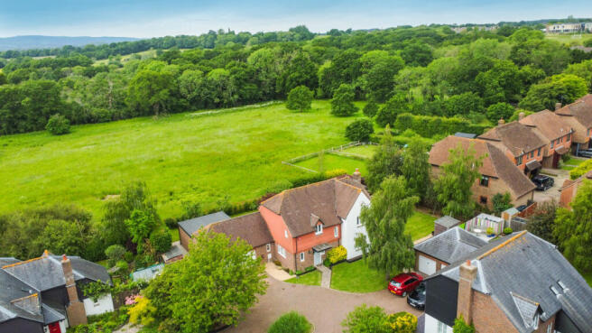 Elevated view of the house with field and woodland behind