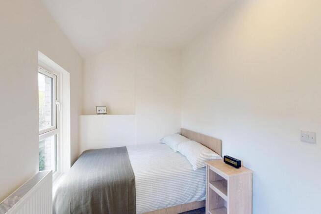 A bright, modern master bedroom featuring a com...