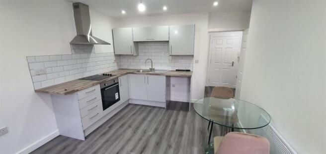 Modern open-plan kitchen with pale cabinetry, s...