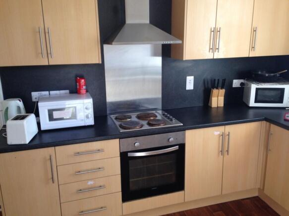 Modern fitted kitchen with light wood cabinets,...