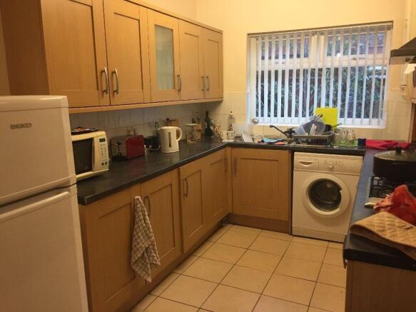 Neat galley kitchen with light wood cabinets, t...