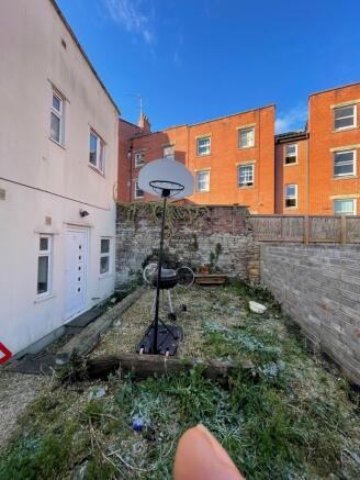 Enclosed rear garden with a paved path and cent...