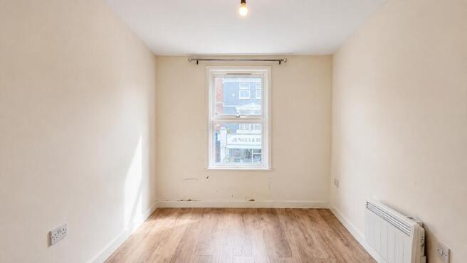 Bright bedroom with wooden flooring and window...