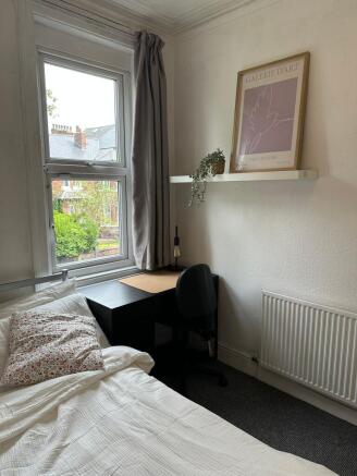 A cozy single bedroom featuring a comfortable b...