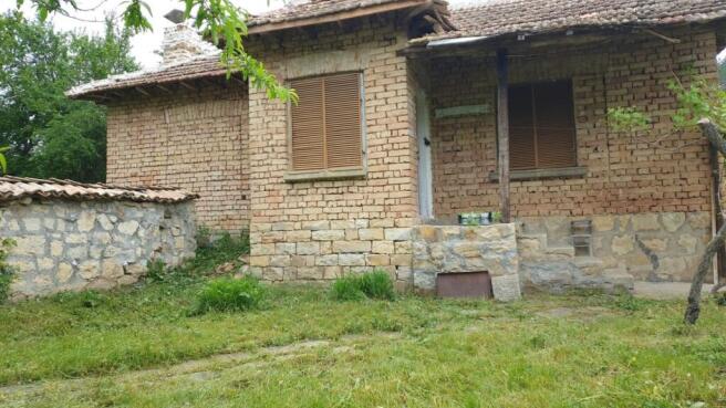 Front facade of the brick house featuring a stone foundation and a small covered porch area