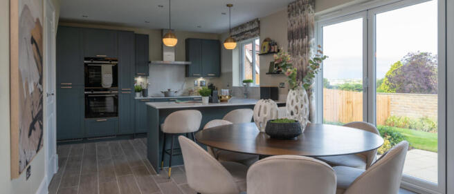 Modern open-plan kitchen and dining area with blue cabinets, beige chairs, and large sliding glass d
