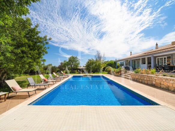 Private pool and main residence of a renovated Algarvian Quinta in Lagoa. Swimming pool surrounded by landscaped gardens and sun loungers.
