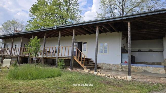 Exterior view of the house showing a long wooden veranda with steps leading to the garden area