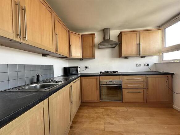 Bright fitted kitchen with light wood cabinets,...