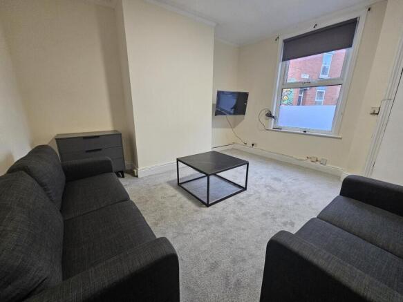 Bright communal lounge with matching sofas, cen...