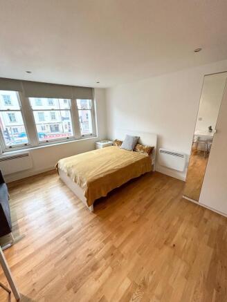 Bright bedroom with wooden floors and large bed...