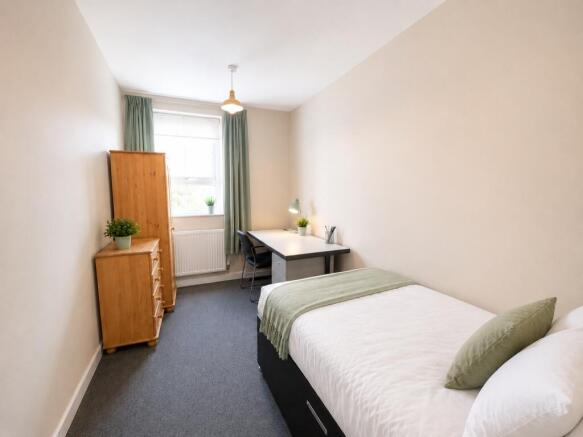 Bright bedroom with large desk and ample storag...