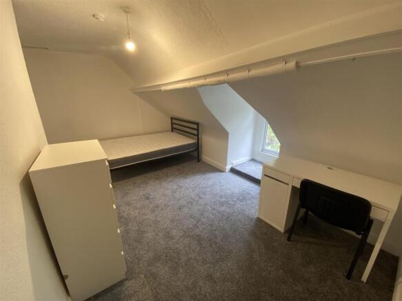 Bright attic room with desk and plush carpet...