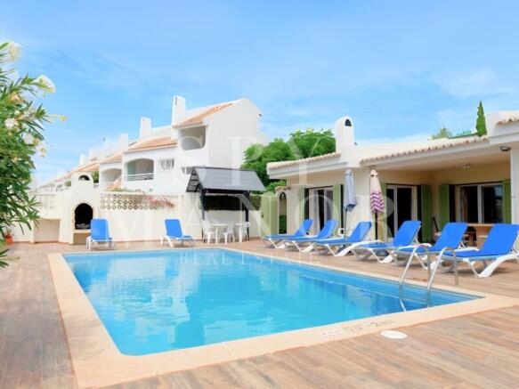 Private pool terrace of a 4-bedroom villa for sale in Carvoeiro, featuring sun loungers, outdoor dining, and a built-in barbecue area. Ideal Algarve holiday retreat.
