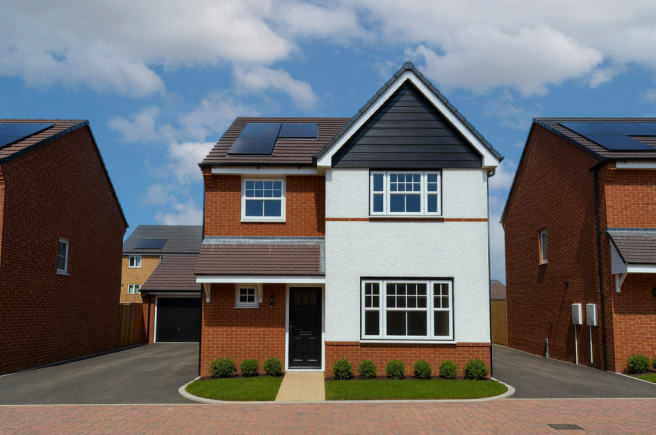 A modern two-story house with white and brick facade and solar panels on the roof stands on a paved