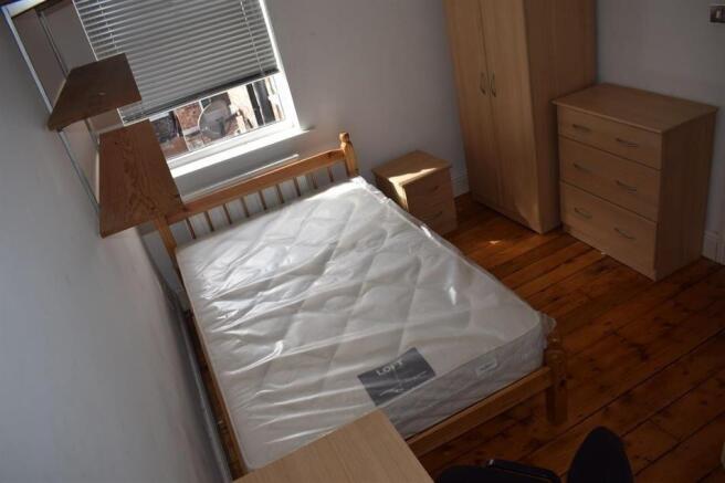 Bright, simply furnished bedroom with wooden fl...