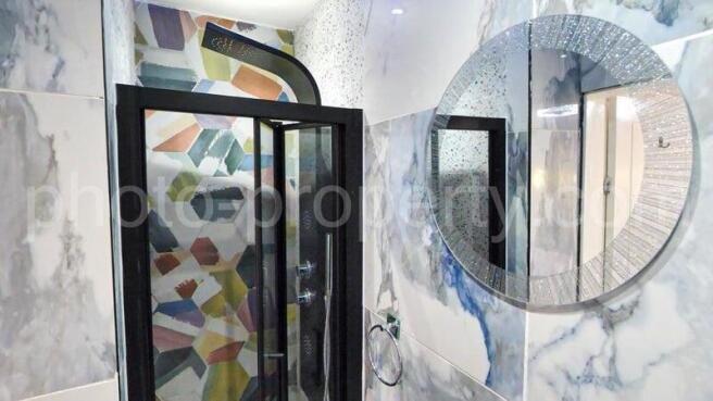 Stylish bathroom with a patterned walk-in showe...