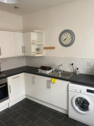 Modern kitchen with white cabinetry, black coun...