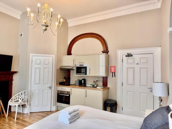 Well-lit room with kitchenette and decorative a...