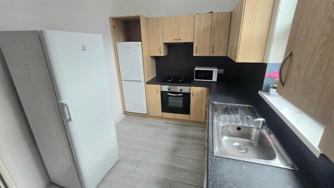 Modern galley kitchen with light wood cabinets,...