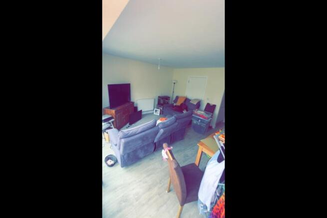 Bright, casual living room with a large TV on a...